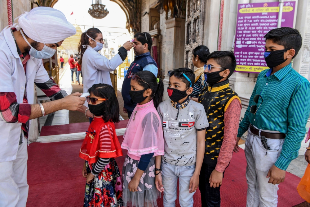 Health workers (L and C) wearing facemasks check the body temperature of devotees amid concerns over the spread of the COVID-19 novel coronavirus, at the entrance of the Durgiana Temple in Amritsar on March 18, 2020. AFP / Narinder Nanu 