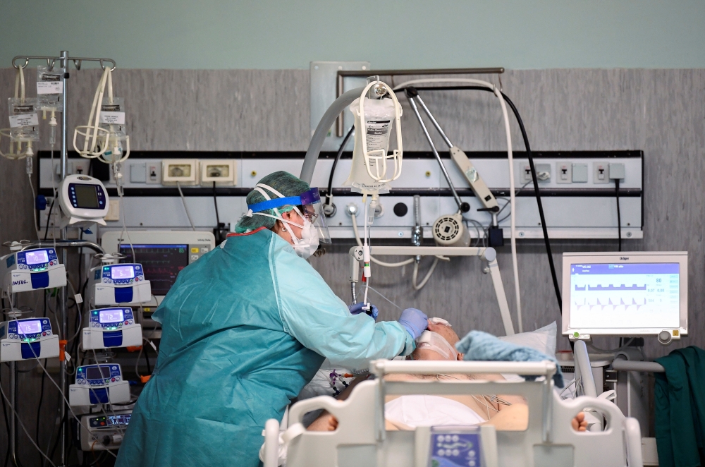 A medical worker wearing a protective mask and suit treats a patient suffering from coronavirus disease (COVID-19) in an intensive care unit at the Oglio Po hospital in Cremona, Italy March 19, 2020. (REUTERS/Flavio Lo Scalzo)