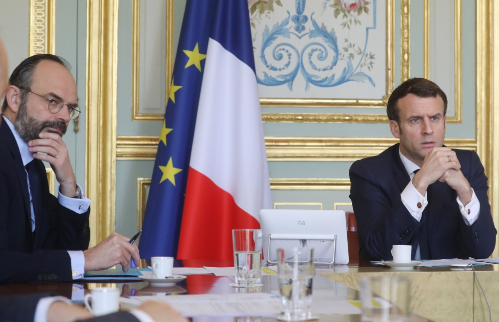 French President Emmanuel Macron (R) and French Prime Minister Edouard Philippe takes part on a videoconference of the 