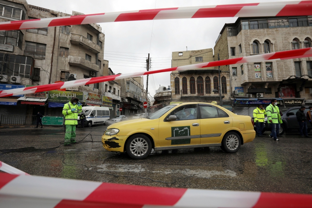 Greater Amman Municipality employees sanitize cars at street amid concerns over the coronavirus disease (COVID-19) spread, outside al Husseini mosque in downtown Amman, Jordan, March 20, 2020. Reuters/Muhammad Hamed
