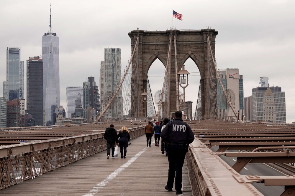 :NEW YORK, NEW YORK, - MARCH 17: A New York City Police officer looks on from the Brooklyn Bridge as it sees significantly less traffic due to coronavirus cases and fears on March 17, 2020 in New York City. Justin Heiman/AFP 