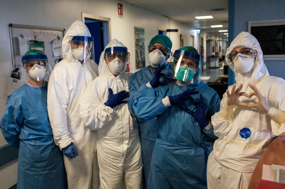 A group of nurses wearing protective mask and gear pose for a group photo prior to their night shift on March 13, 2020 at the Cremona hospital, southeast of Milan, Lombardy. AFP PHOTO / PAOLO MIRANDA