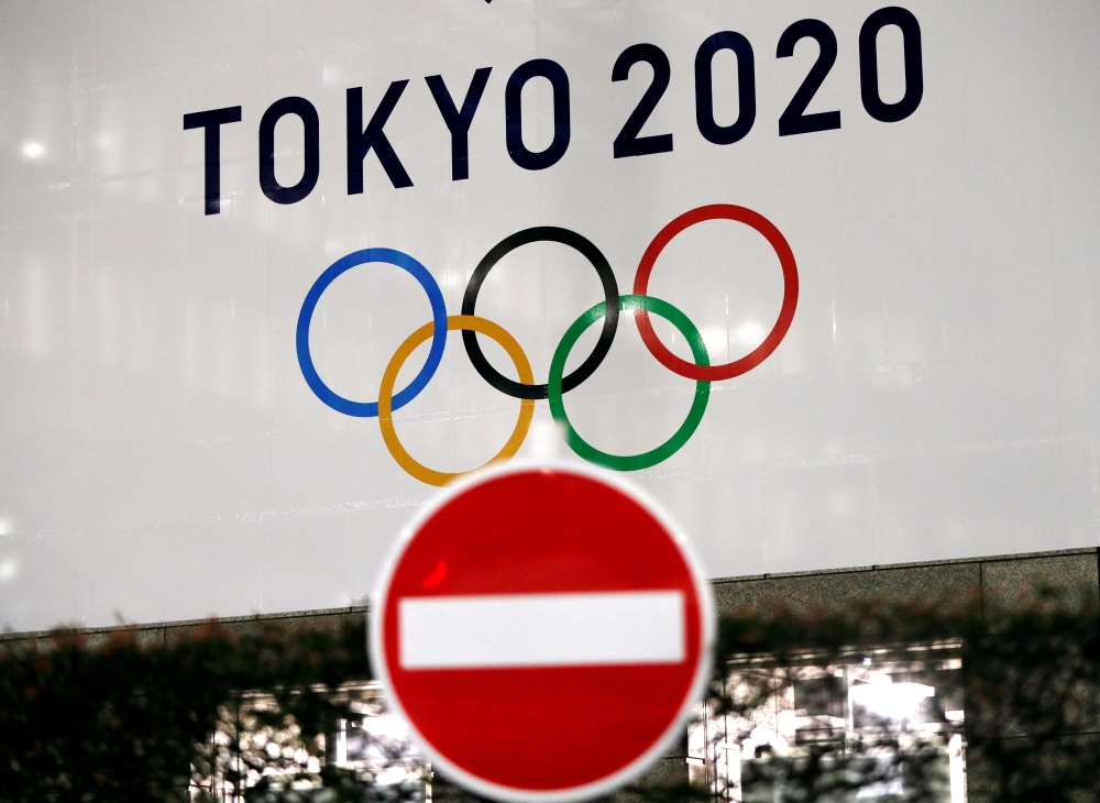 FILE PHOTO: A banner for the upcoming Tokyo 2020 Olympics is seen behind a traffic sign, following an outbreak of the coronavirus disease (COVID-19), in Tokyo, Japan, March 23, 2020. REUTERS/Issei Kato