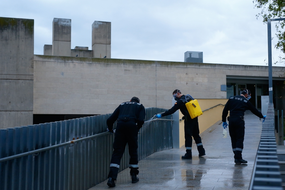 A member of the Military Emergencies Unit (UME) carries out a general disinfection at a local market in Badalona near Barcelona on March 25, 2020. AFP / PAU BARRENA