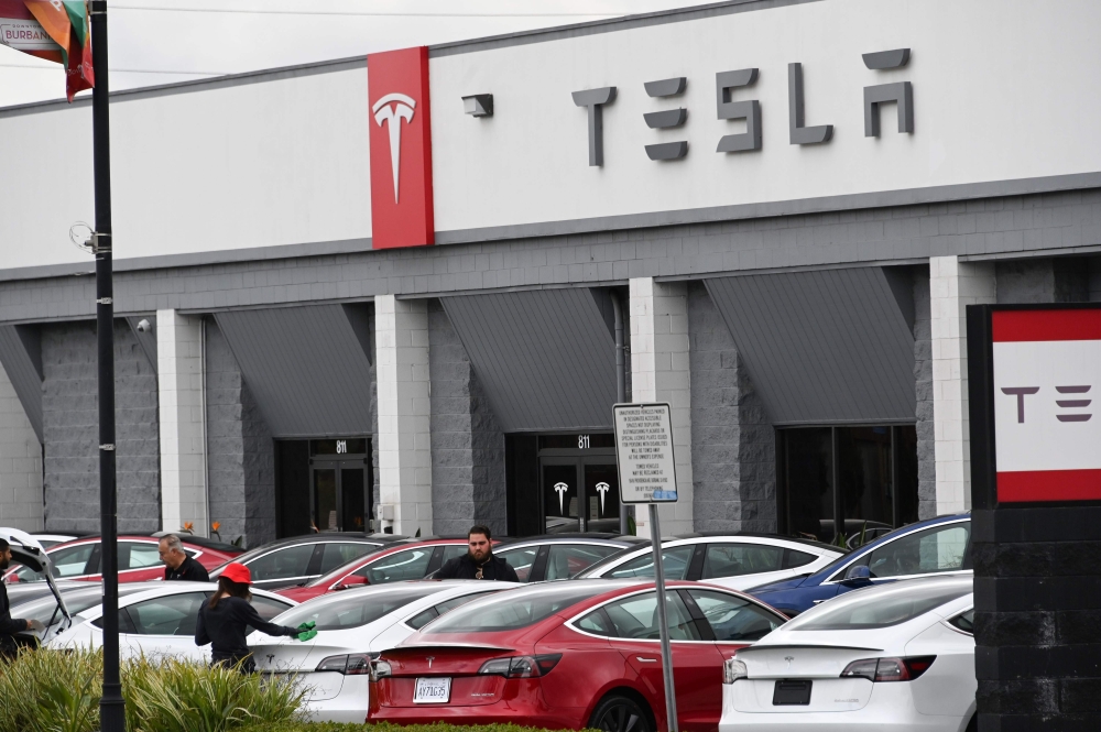 Telsa employees work outside a tesla showroom in Burbank, California, March 24, 2020. / AFP / Robyn Beck
