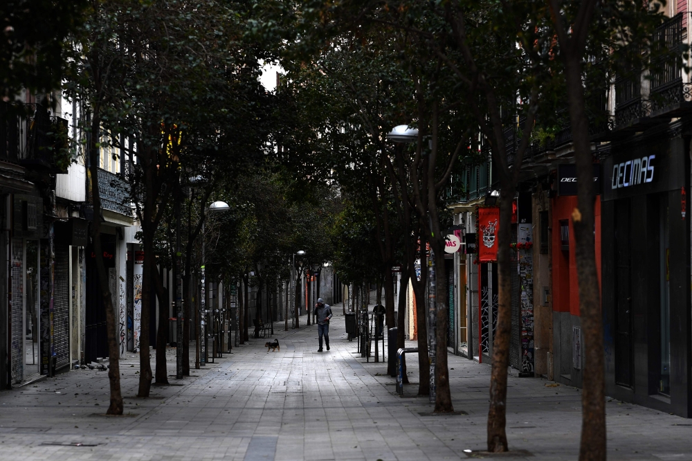 A man walks his dog in an empty street in Madrid on March 27, 2020 amid a national lockdown to fight the spread of the COVID-19 coronavirus. AFP / Gabriel Bouys