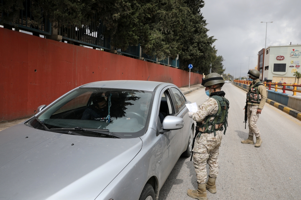Jordanian soldiers check a car as they guard a check point in the northern governorate of Irbid, as the city has been isolated and people were banned from entering it, after the number of coronavirus disease (COVID-19) cases have increased in the area, Ir