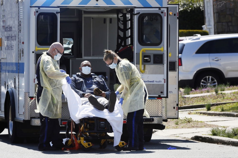 Emergency Medical Technicians (EMT) lift a patient that was identified to have coronavirus disease (COVID-19) into an ambulance while wearing protective gear, as the outbreak of coronavirus disease (COVID-19) continues, in New York City, New York, U.S., M