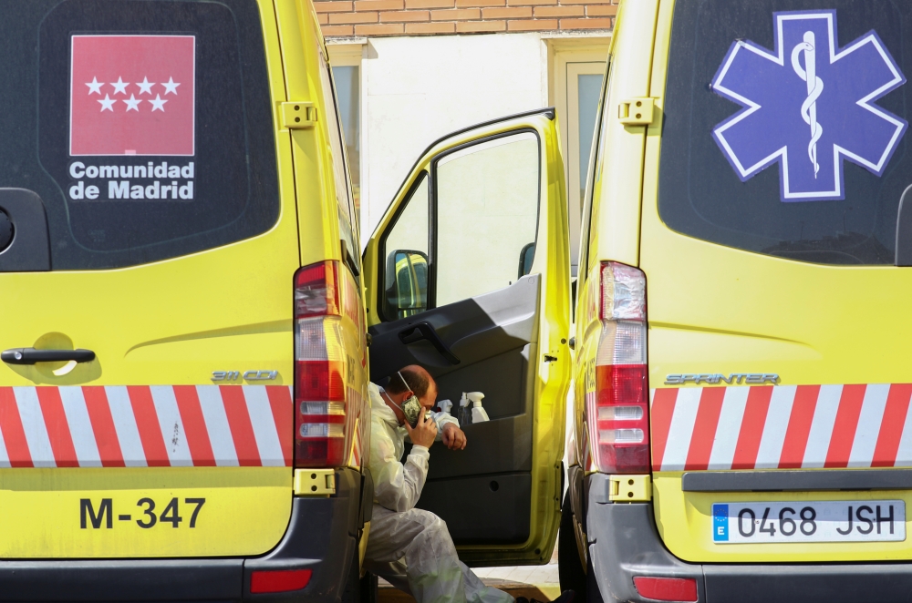 An ambulance driver wearing a protective face mask and suit takes a break near the emergency unit at 12 de Octubre hospital during the coronavirus disease (COVID-19) outbreak in Madrid, Spain March 28, 2020. REUTERS/Sergio Perez 