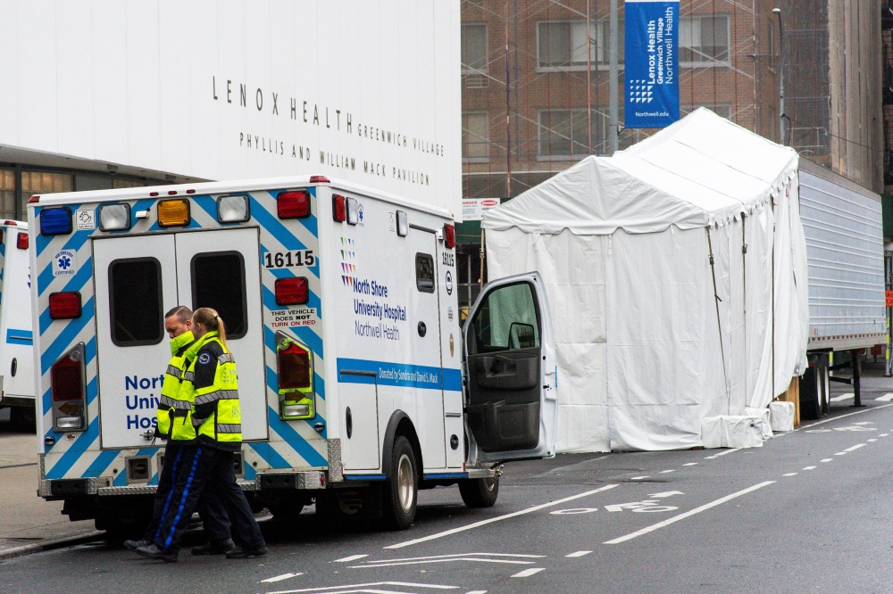 Paramedics walk next to a makeshift morgue set outside Lenox Health Medical Pavilion as the coronavirus disease (COVID-19) outbreak continues in New York, U.S., March 29, 2020. REUTERS/Eduardo Munoz
