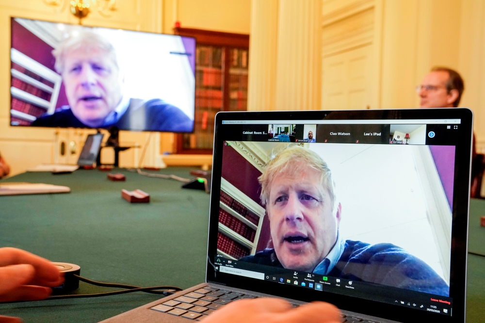 Boris Johnson appears on monitors for COVID-19 meeting in London, Britain March 28, 2020. Andrew Parsons/10 Downing Street/Handout via Reuters