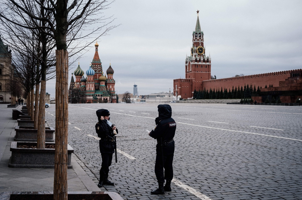 Police officers wearing face masks patrol on the empty Red square, with the St. Basil's Cathedral (L) and Kremlin's Spasskaya Tower (R) in the background, in Moscow on March 30, 2020. AFP / Dimitar DILKOFF
