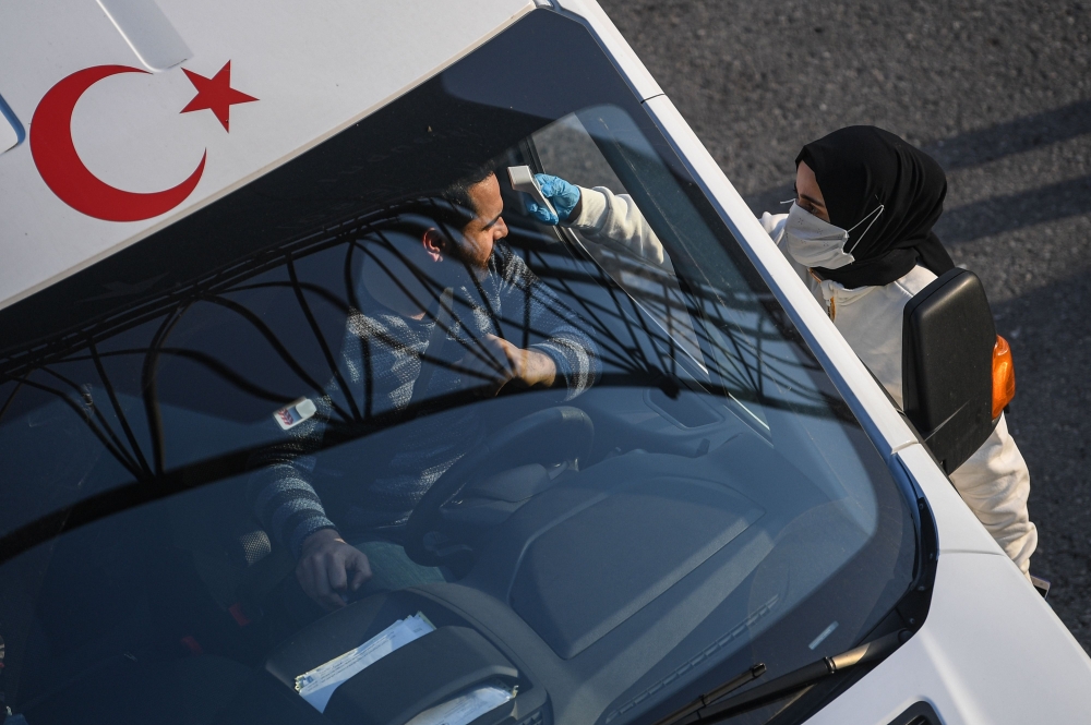 A Turkish health official checks the temperature of a driver at a check point, on the Asian side ,entry of Istanbul on March 30,2020. President Recep Tayyip Erdogan called on Turks to stay at home and adapt themselves to 