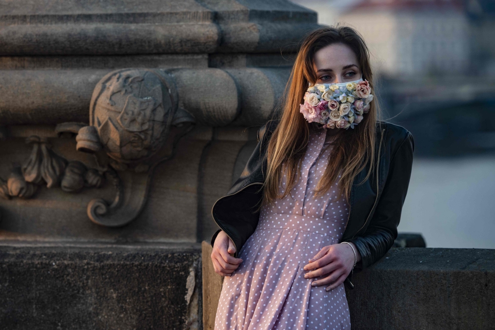 :A woman wearing a face mask stands on the Charles Bridge on March 28, 2020, in Prague, where most activities slowed down or came to a halt due to the spread of the novel coronavirus COVID-19. / AFP / Michal Cizek
