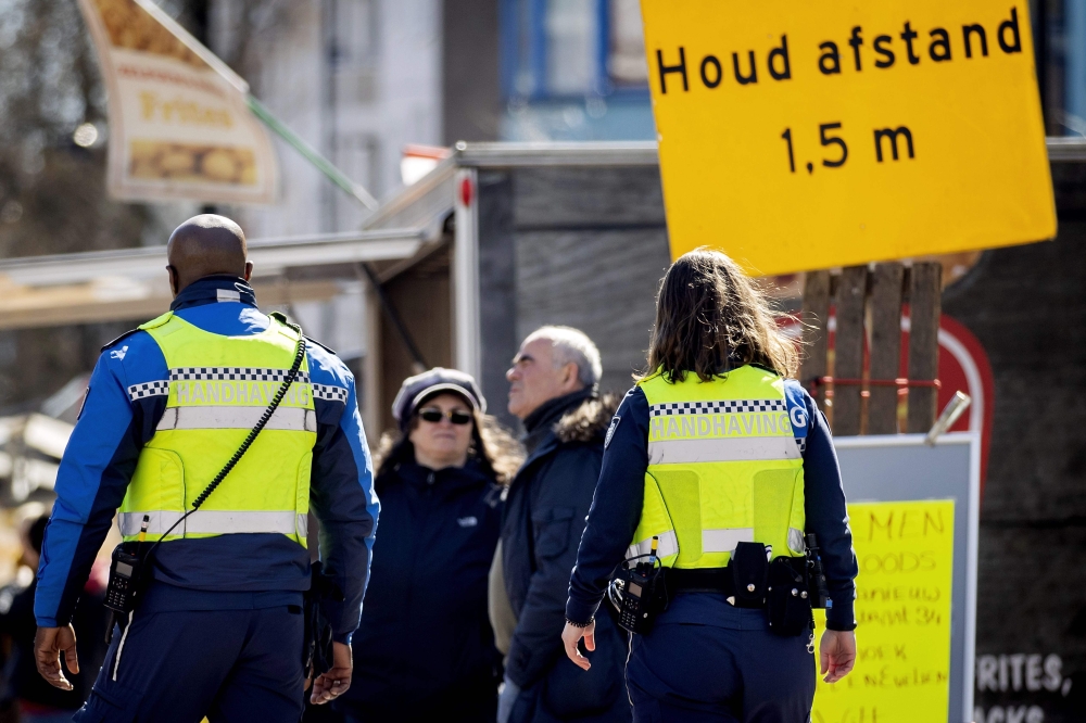 Dutch policemen carry out contols in order to check if people follow the measures put in place in Amsterdam, The Netherlands, on March 31, 2020, amid the outbreak of COVID-19 (novel coronavirus). Netherlands OUT / AFP / ANP / Koen Van Weel