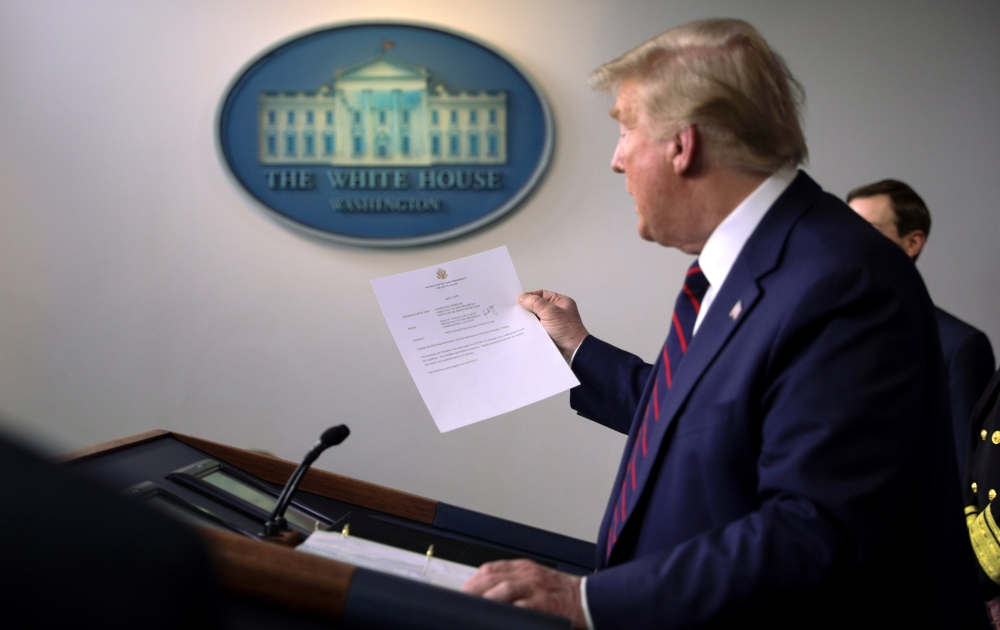 U.S. President Donald Trump holds a letter from White House physician Commander Sean Conley that reports that the president has tested negative a second time for coronavirus disease during a use of the new 15-minute result test at the White House in Washi