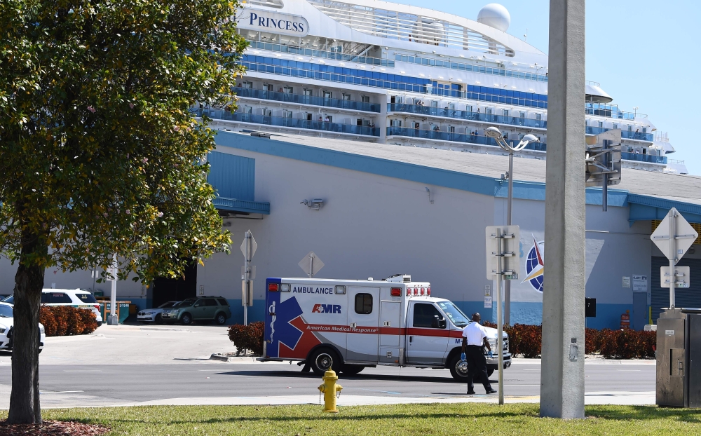 An ambulance takes a patient from the cruise ship Coral Princess to the hospital as the ship is docked at the Port of Miami, Florida, on April 4, 2020, after receiving permission from the US Coast Guard. / AFP / CHANDAN KHANNA