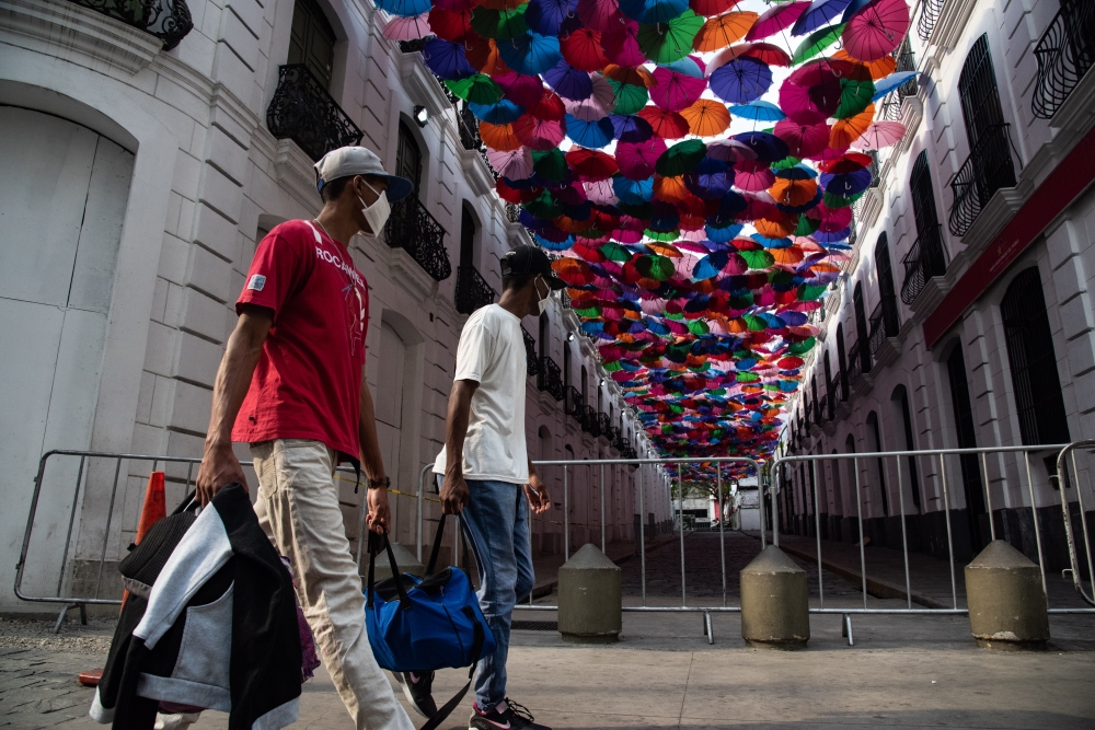 CARACAS, Venezuela - APRIL 02: Two men pass by a down town street covered with umbrellas which is empty as a preventive measure against the new type of coronavirus (COVID-19) pandemic in Caracas, Venezuela on April 02, 2020. ( Carolina Cabral Fernandez - 