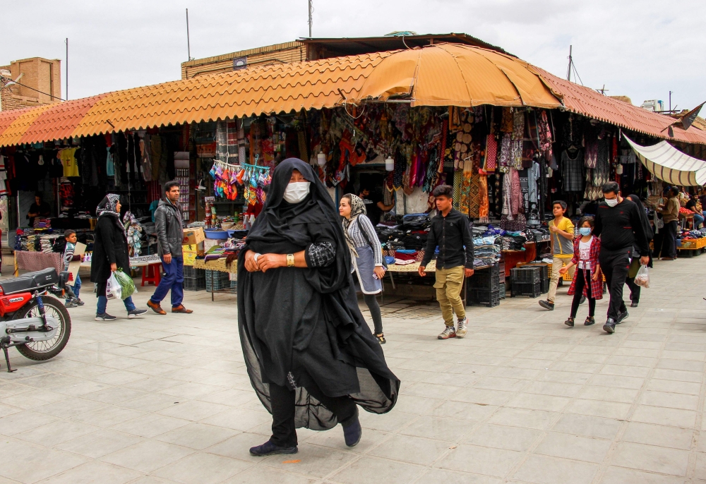 Iranians, some wearing personal protective equipment, walk past shops in the southeastern city of Kerman on April 11, 2020, amid the coronavirus (COVID-19) pandemic. AFP / ISNA
