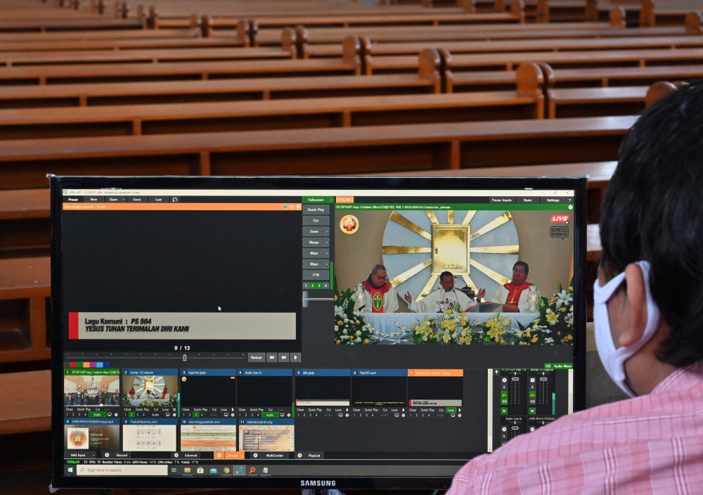 A man tends to a live broadcast of clergy conducting Easter mass in an empty church and streamed online as part of social distancing measures amidst the COVID-19 coronavirus pandemic in Jakarta on April 12, 2020. AFP / ADEK BERRY
