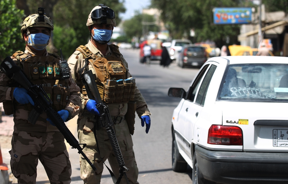 Iraqi soldiers stand at a checkpoint in the Adhamiya district of Baghdad on April 13, 2020 as Iraq imposed a curfew during the coronavirus COVID-19 pandemic. / AFP / AHMAD AL-RUBAYE