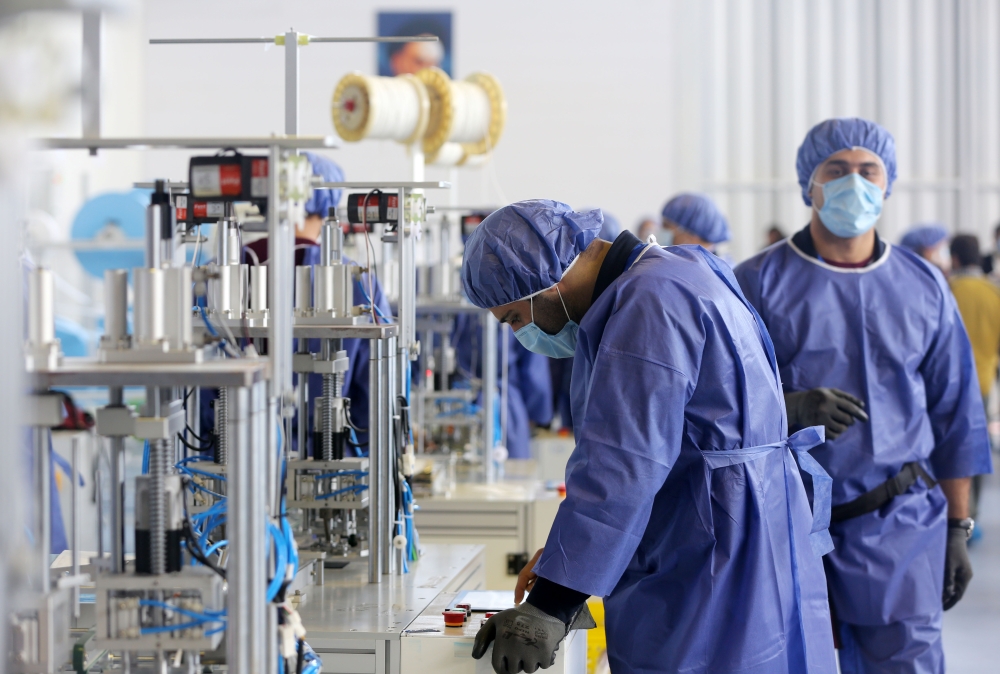 Tehran, IRAN - APRIL 14: A worker, wearing a face mask, produces masks to be used as a preventive measure against the coronavirus (COVID-19) pandemic at a factory, aiming to produce four million masks a day, at Eshtehard Industrial Town in Eshtehard, some