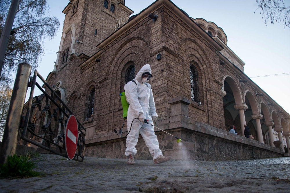 :TOPSHOT - A members of the Sofia's Municipality disinfects the area around the St. Nedelya Church in Sofia, to prevent the spread of the COVID-19, the novel coronavirus on April 11, 2020. . / AFP / NIKOLAY DOYCHINOV