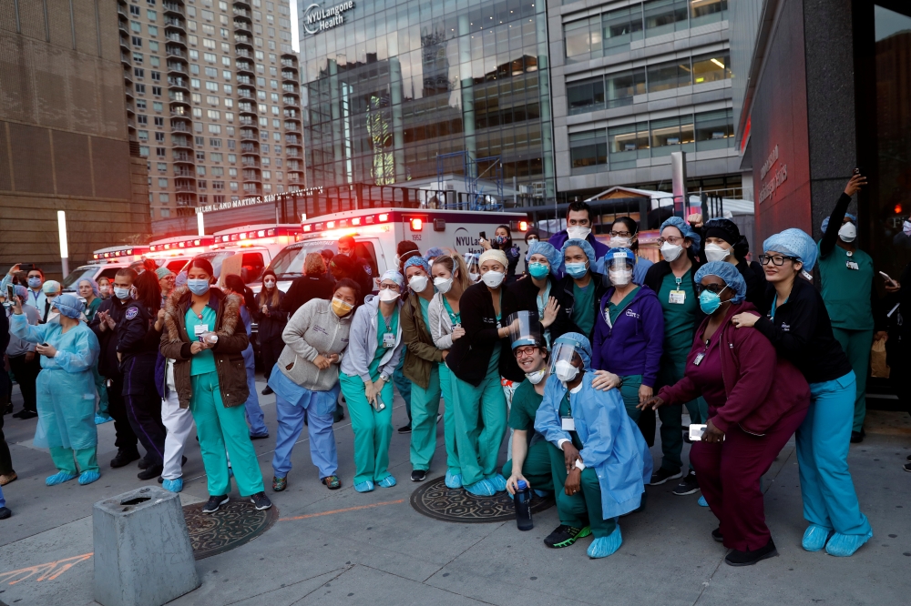 Healthcare workers pose for pictures together outside NYU Langone Medical Center on 1st Avenue in Manhattan as New York Police Department (NYPD) Mounted Police and other units came to cheer and thank healthcare workers at 7pm during the outbreak of the co