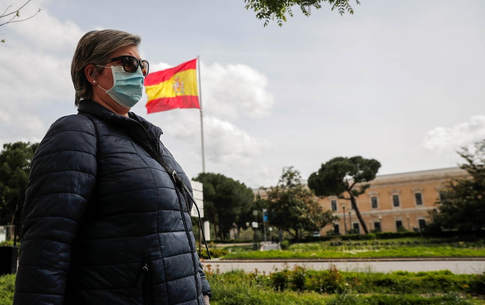 A woman wearing a medical mask walks at nearly empty Columbus Square after precautions against the spread o in Madrid, Spain on April 17, 2020. Burak Akbulut - Anadolu 