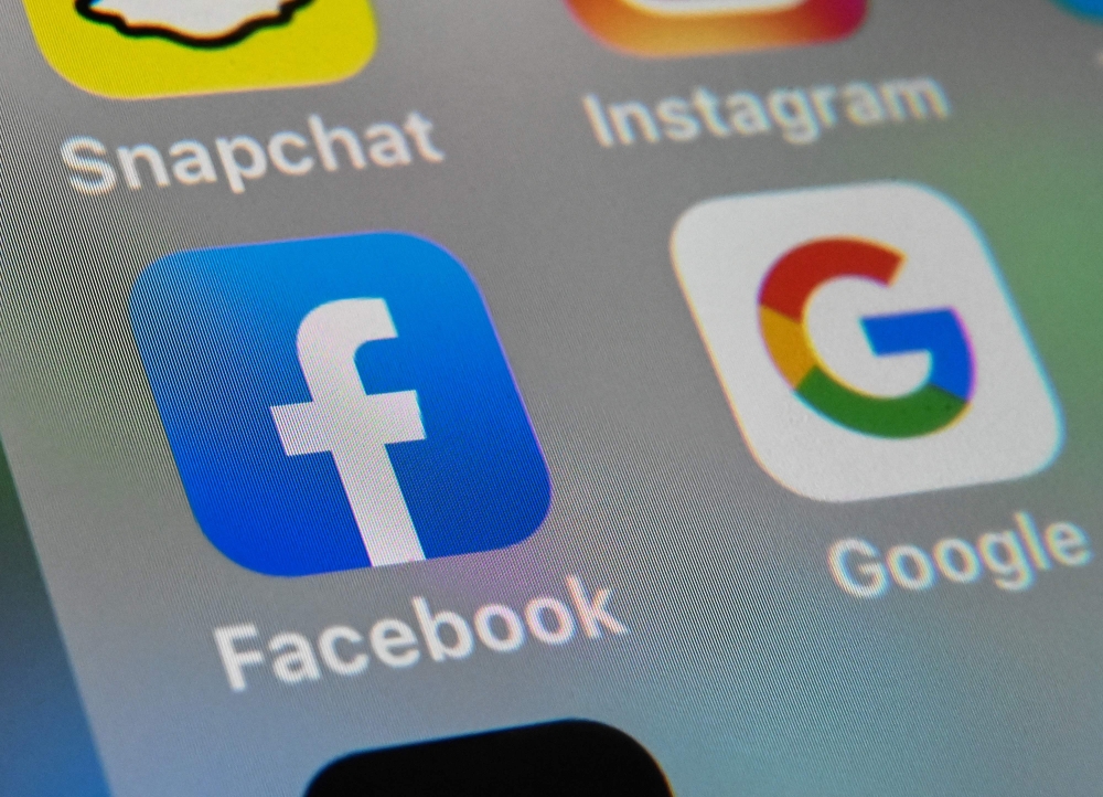 (FILES) This file picture taken on October 1, 2019 shows the logos of mobile apps Facebook and Google displayed on a tablet in Lille. Australia announced on April 20, 2020 it will begin forcing Google and Facebook to pay news companies for content, in a l