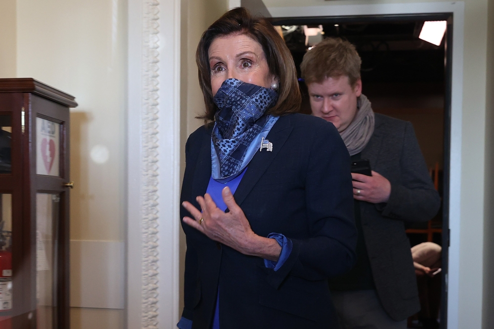 House Speaker Nancy Pelosi (D-CA) wears a scarf over her mouth and nose to guard against the coronavirus as she and her Deputy Chief of Staff Drew Hammill leave a news conference with Minority Leader Charles Schumer (D-NY) at the U.S. Capitol April 21, 20