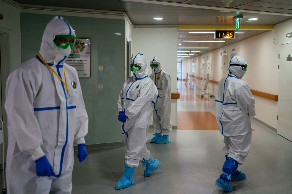 TOPSHOT - Medical workers wearing protective equipment walk in a hall of Moscow's K+31 private hospital, which has switched over entirely to treating coronavirus patients, on April 20, 2020. / AFP / Dimitar DILKOFF