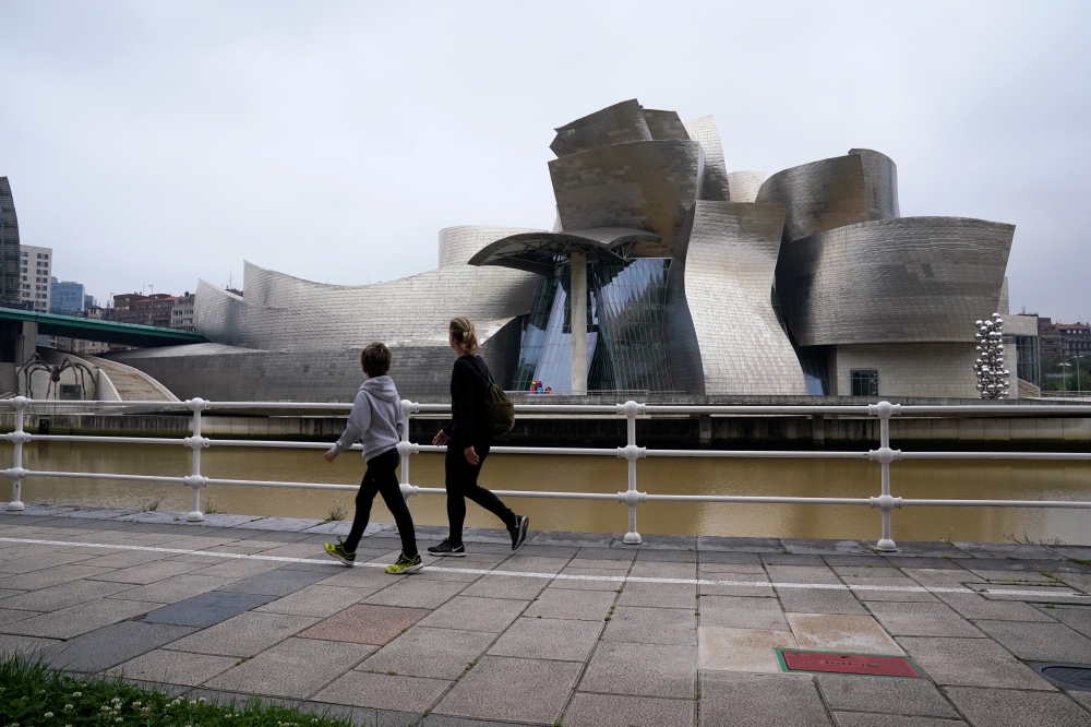 A family walks past the Guggenheim Museum, after restrictions were partially lifted for children for the first time in six weeks, during the coronavirus disease (COVID-19) outbreak in Bilbao, Spain, April 26, 2020. REUTERS/Vincent West