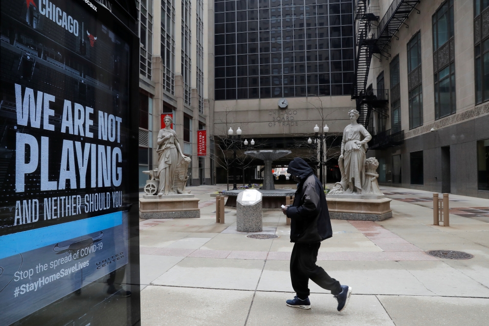 A man walks by a sign in front of the closed Chicago Board of Trade as the spread of the coronavirus disease (COVID-19) continues, in Chicago, Illinois, U.S., April 23, 2020. REUTERS/Shannon Stapleton