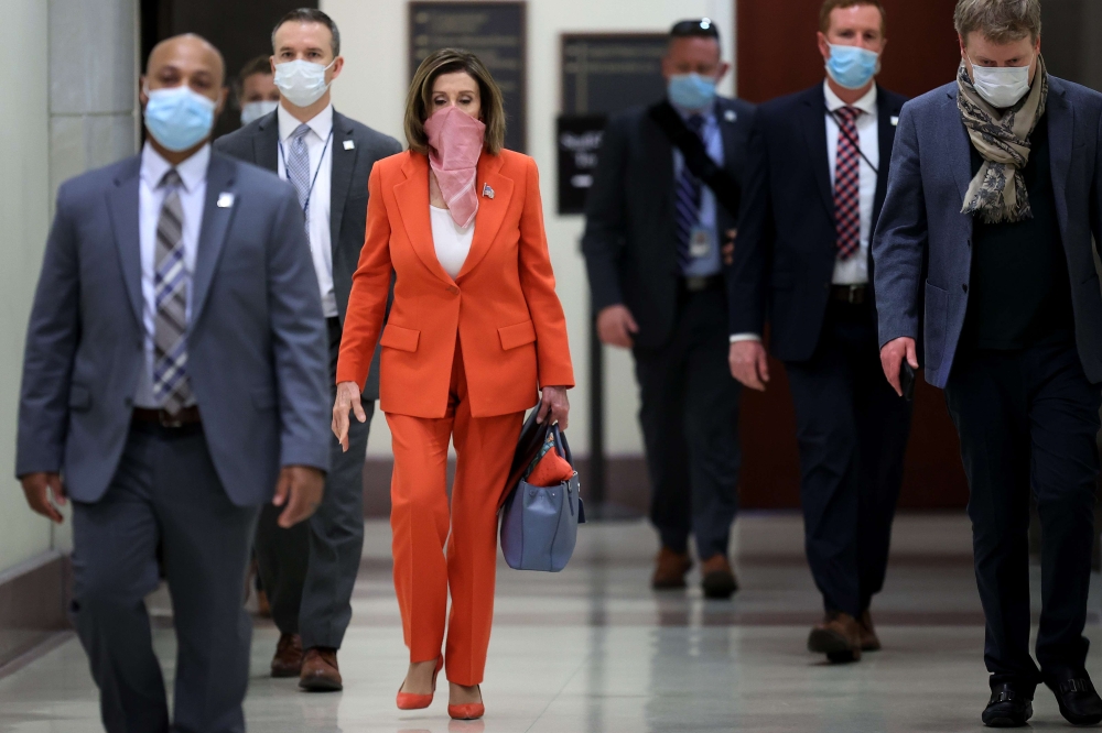 Wearing a scarf over her mouth and nose, Speaker of the House Nancy Pelosi (D-CA) is surrounded by security and staff as she arrives for her weekly news conference during the novel coronavirus pandemic at the U.S. Capitol April 24, 2020 in Washington, DC.