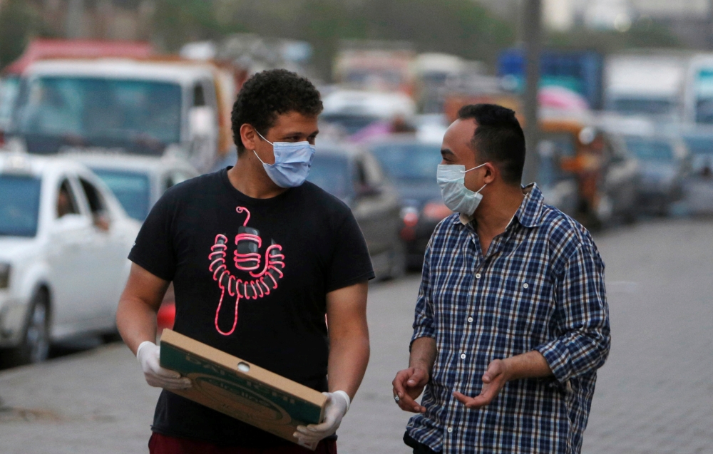Men wearing face masks walk along a street before curfew, during the global outbreak of the coronavirus disease (COVID-19), in Shubra El Kheima, Al Qalyubia Governorate, north of Cairo, Egypt, April 27, 2020. REUTERS/Mohamed Abd El Ghany