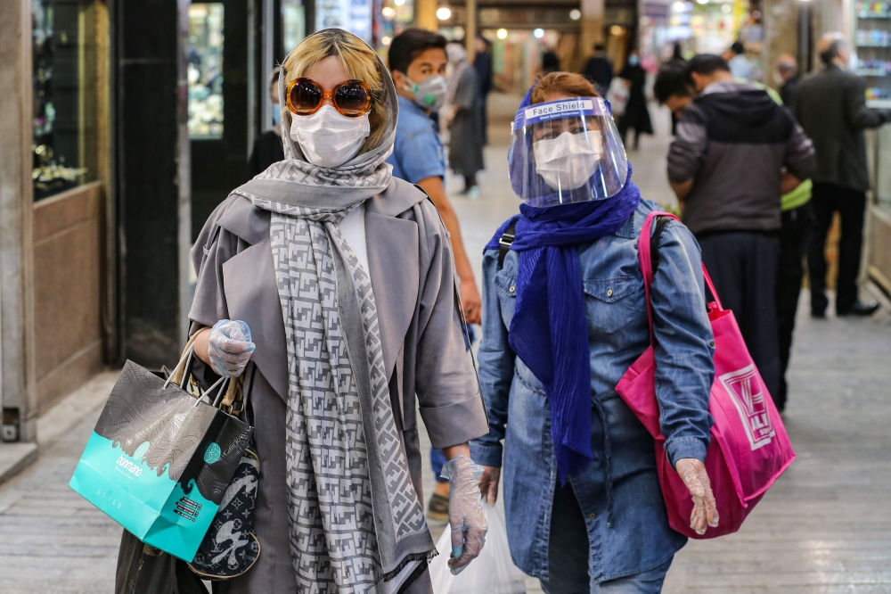 TOPSHOT - Shoppers clad in protective gear, including face masks and shields and latex gloves, due to the COVID-19 coronavirus pandemic, walk through the Tajrish Bazaar in Iran's capital Tehran on April 25, 2020 during the Muslim holy month of Ramadan. / 