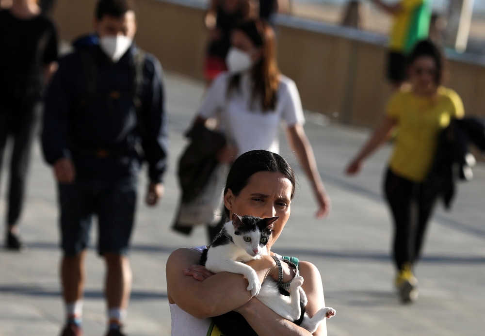 A woman walks as she holds a cat during the hours in which individual exercise is allowed outdoors, for the first time since the lockdown was announced, amid the coronavirus disease (COVID-19) outbreak, in Barcelona, Spain, May 2, 2020. REUTERS/Nacho Doce