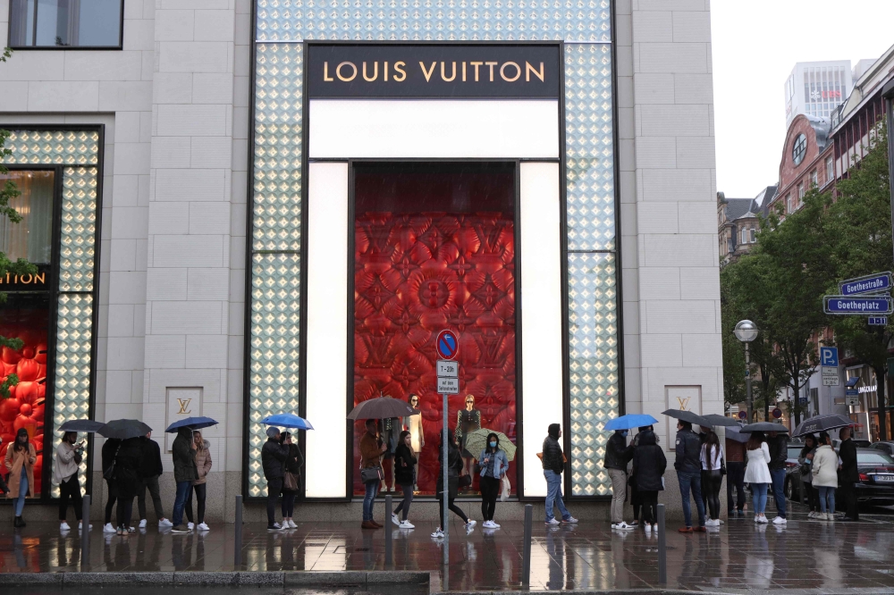 People wait in line to get into a Louis Vuitton store on May 2, 2020, in Frankfurt am Main, western Germany, amid the coronavirus COVID-19 pandemic. / AFP / Yann Schreiber