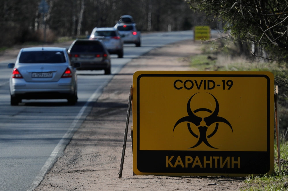 Cars drive past a sign reading 'COVID-19 Quarantine' on a road towards Pervomayskoye settlement during the coronavirus disease (COVID-19) outbreak in Leningrad Region, Russia May 5, 2020. REUTERS/Anton Vaganov
