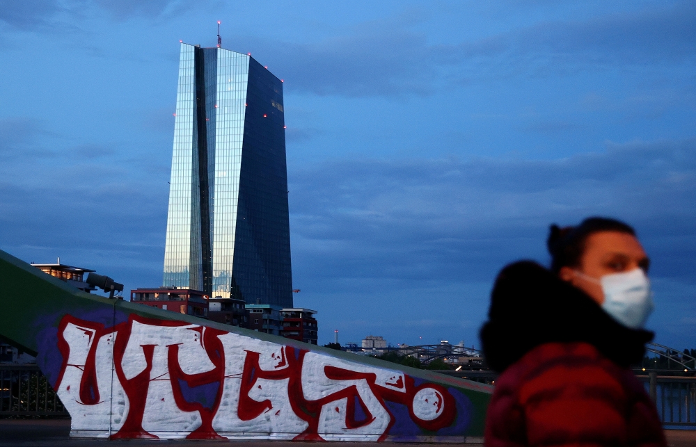 FILE PHOTO: A woman, wearing a protective mask walks past the head quarter of the European Central Bank (ECB) during sunset in Frankfurt, Germany, April 29, 2020, as the spread of the coronavirus disease (COVID-19) continues. REUTERS/Kai Pfaffenbach/File 