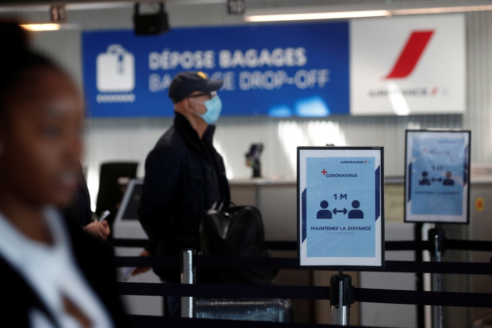 Passengers wearing protective face masks maintain social distance as they queue in Terminal 2E at Paris Charles de Gaulle airport in Roissy-en-France during the outbreak of the coronavirus disease (COVID-19) in France, May 6, 2020. REUTERS/Benoit Tessier