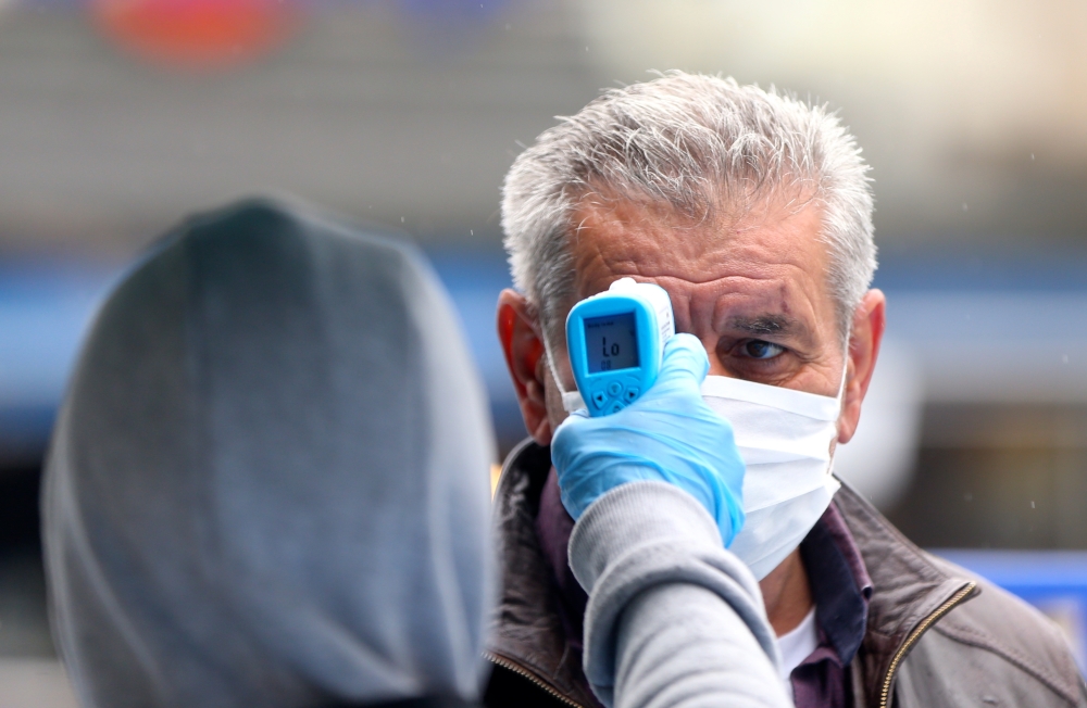 DUZCE, TURKEY - MAY 5: An officer checks the body temperature of a man wearing mask as people continue stay at home as a precaution against coronavirus (Covid-19) pandemic in Duzce, Turkey on May 5, 2020. ( Ömer Ürer - Anadolu Agency 