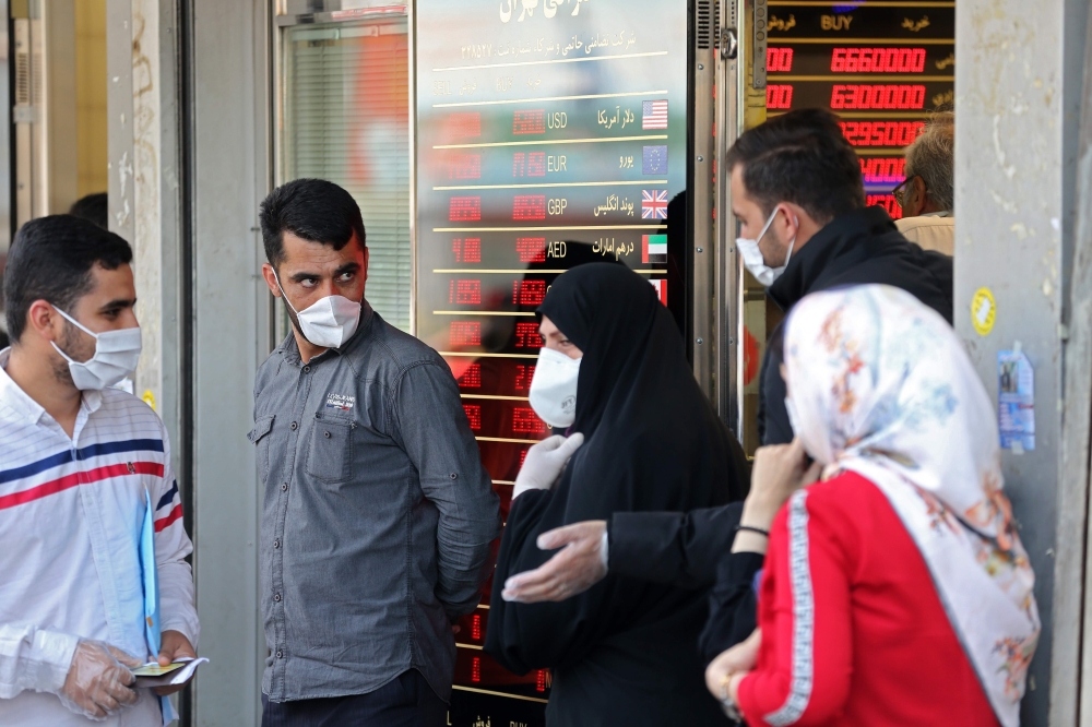 Iranians, wearing protective masks without observing social distancing, queue outside a money exchange office in the capital Tehran on May 9, 2020, during the coronavirus (COVID-19) pandemic.   AFP / ATTA KENARE