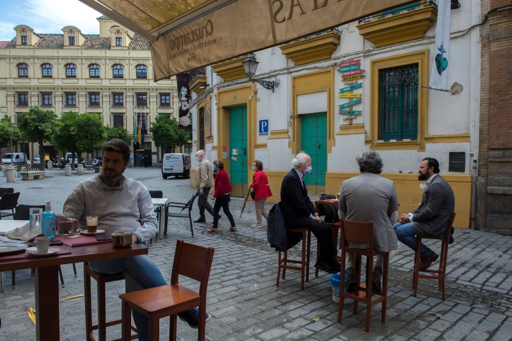 People have breakfast at a cafe in Sevilla on May 11, 2020 as Spain moved towards easing its strict lockdown in certain regions.  / AFP / CRISTINA QUICLER