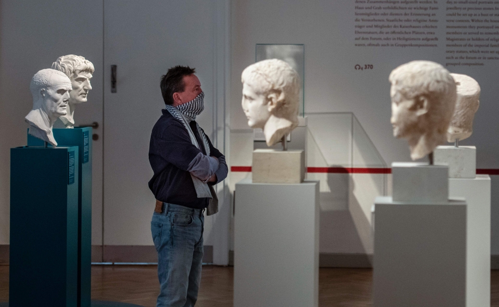 A visitor checks out roman busts at the Altes Museum (Old Museum) in Berlin on May 12, 2020, after the museum re-opened its doors to the public following a relaxation of lockdown restrictions due to the new coronavirus COVID-19 pandemic. / AFP / John MACD