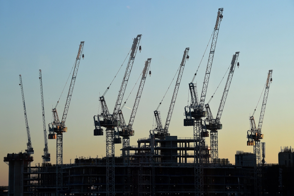 The sun sets beyond construction cranes standing over the building site for new apartments and a retail complex, at the Battersea Power Station redevelopment site in south London on May 14, 2020 following an easing of the novel coronavirus COVID-19 lockdo
