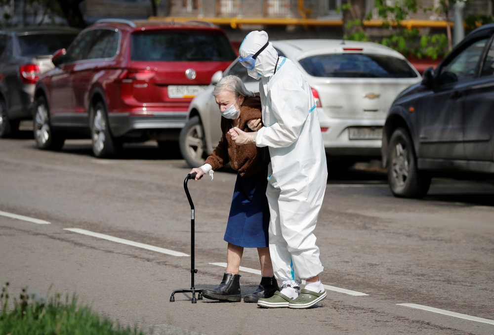 :A medical specialist, wearing a protective suit amid the coronavirus disease (COVID-19) outbreak, assists an elderly woman to cross a road in Moscow, Russia May 14, 2020. REUTERS/Shamil Zhumatov
