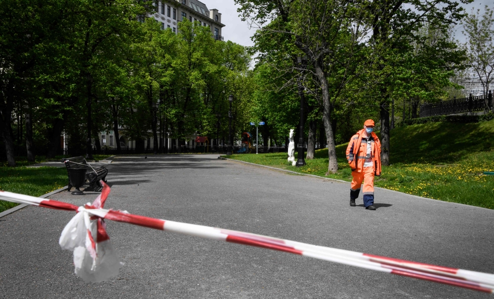 :A municipal worker walks along a boulevard in central Moscow on May 14, 2020, amid the outbreak of COVID-19, caused by the novel coronavirus. Moscow's streets remain depopulated despite half a million employed in construction and industry sectors were al