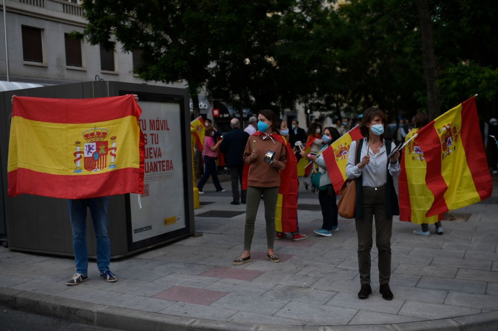 People holding Spanish flags bang pans as a protest against the measures taken by the Spanish government during the national lockdown to prevent the spread of the COVID-19 disease, on May 17, 2020 in Madrid. / AFP / OSCAR DEL POZO
